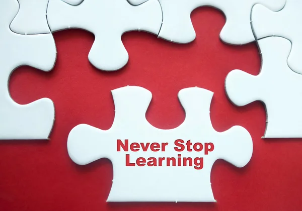 Pedaços de puzzle sobre fundo vermelho com citação motivacional "Nunca pare de aprender " — Fotografia de Stock