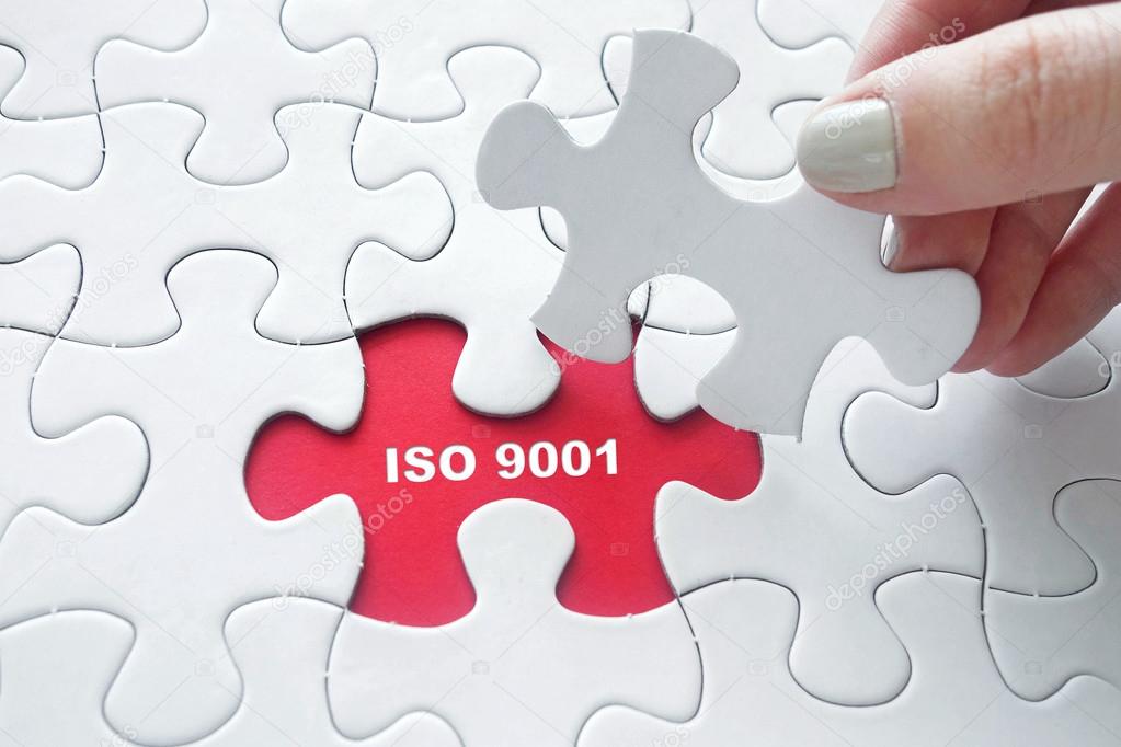 Close up of girl's hand placing the last jigsaw puzzle piece with word ISO 9001