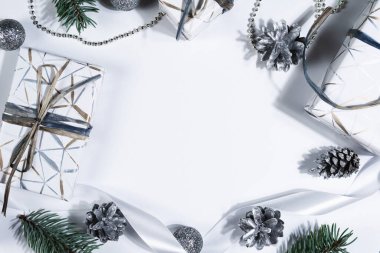 Noel soyut arka planı, kopyalama alanı. Gümüş kozalaklar, köknar ağacı dalları ve beyaz arka planda dönen hediye kutusu. Yeni yıl hediyeleri, festival ve tatil alışverişi kavramı