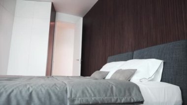 Temiz beyaz yastıklı, gri battaniyeli, arka planda tahta duvarlı modern çift kişilik yatak. Lüks yatak odası, otel servisi kavramları..
