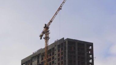 İnşaat kulesi vinci gökdelenin çatısında çalışıyor. Bir apartmanın inşaat alanı. Zaman aşımı.