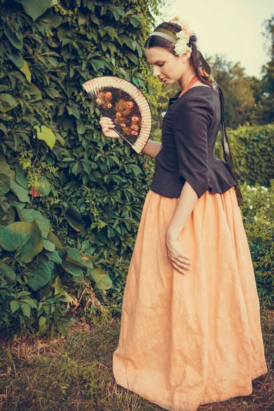 Portrait of brunette woman dressed in historical Baroque clothes with old fashion hairstyle, outdoors. Middle class medieval dress