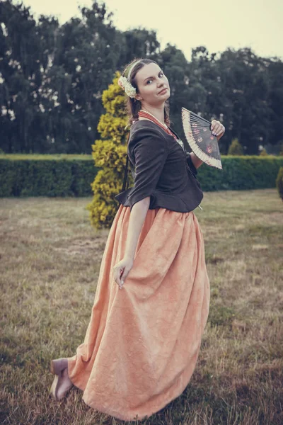 Portrait of brunette woman dressed in historical Baroque clothes with old fashion hairstyle, outdoors. Middle class medieval dress