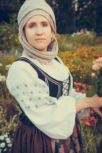 Portrait of woman dressed in historical Baroque clothes with a headscarf, outdoors. Middle class medieval dress