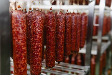 Fabrikada tütsülenmiş sosis üretim hattı. Domuz eti ve salam endüstrisi. Lezzetli yiyecekler ve yiyecekler.