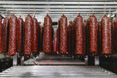 Fabrikada tütsülenmiş sosis üretim hattı. Domuz eti ve salam endüstrisi. Lezzetli yiyecekler ve yiyecekler.