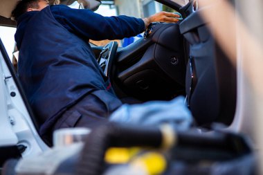 Çalışkan bir işçi beyaz bir arabayı yıkamayı yeni bitiriyor. Şimdi özel bir mendille içeriyi siliyor..