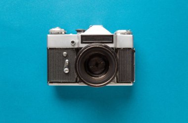 Eski bir analog kameranın önünde. Ve kameranın mavi turkuaz bir arka planı var. Kamera çok eski ve mahvolmuş..