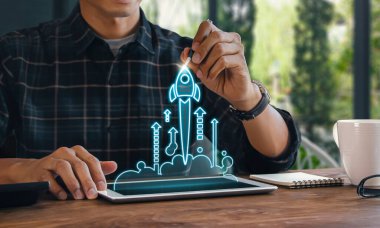 İş kurma, başlama, yeni proje ya da yeni fikir konsepti. Tahta bloklar, piramit şeklinde düzenlenmiş roket grafiği fırlatılıyor ve bir adam en üsttekini tutuyor..