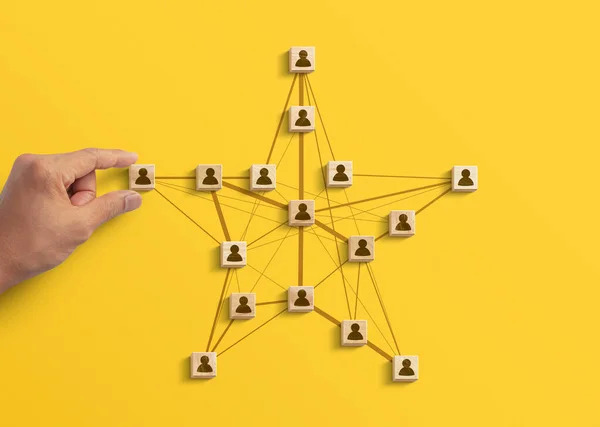 Human resources management, teamwork management or business strategy to success concept. Hand is arranging wooden blocks with human icon in polygon star shape network on yellow background.