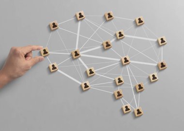 İnsan kaynakları yönetimi, takım çalışması yönetimi ya da başarı konseptine iş stratejisi. El, gri arkaplandaki çokgen beyin şeklindeki insan simgesiyle ahşap blokları düzenliyor..