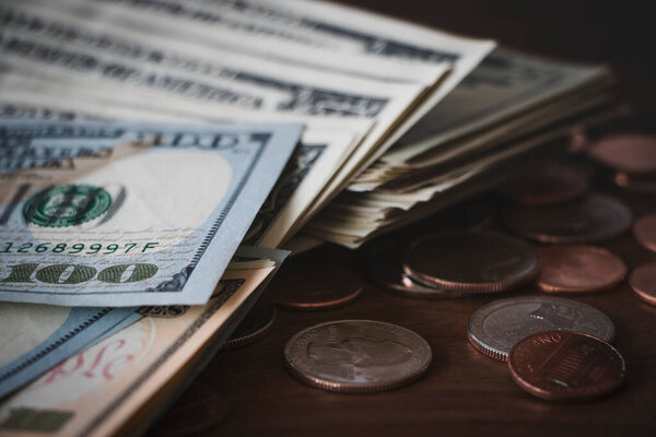 Financial, banking or savings concept. Dollar banknotes and coins on wood desk background.