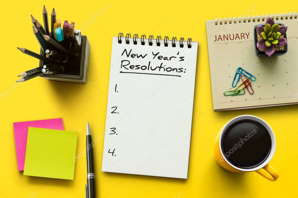 New Year resolutions, goals or action plan concept. Notebook on office table with calendar, coffee, plant and stationery. Flat lay (top view) notepad for input copy or text on yellow background.