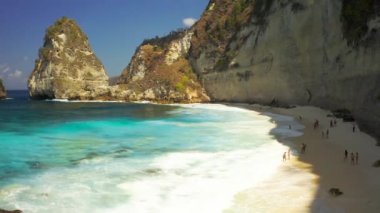 Ünlü plaj ve turistler Endonezya 'nın Nusa Penida adasındaki Elmas plajında yüzüyorlar. Hava görüntüsü 4K