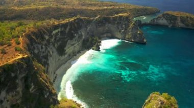 Okyanus dalgaları, uçurumlar ve Endonezya 'daki Bali' de Nusa Penida adasında tropikal beyaz kum plajı. Hava görüntüsü 4K