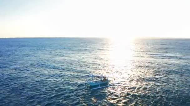 Риболовецький човен у блакитному морі в час сходу сонця. БАЛІ, Індонезія. 15 липня 2019 року. Повітряний вид 4K — стокове відео
