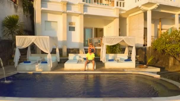 Casal mulher e homem desfrutando de um sol na piscina infinita no Amed, Bali, Indonésia. Férias e conceito de verão. Vista aérea 4K — Vídeo de Stock