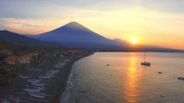 Pôr do sol vista panorâmica do oceano e do vulcão Agung da aldeia de Amed, Bali, Indonésia. Vista aérea 4K — Vídeo de Stock