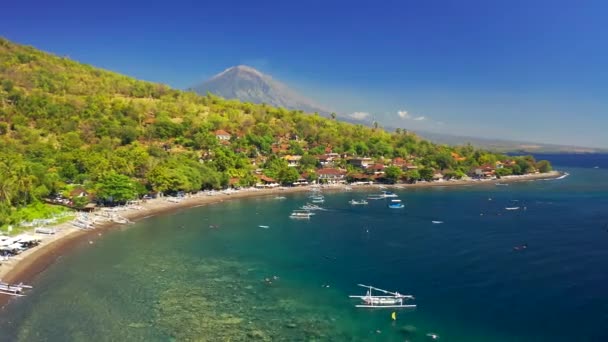 Низкоугольный беспилотник движется над лодками на море в заливе Джемелук на заднем плане вулкана Агунг, Амед, Бали, Индонезия. Вид с воздуха 4K — стоковое видео