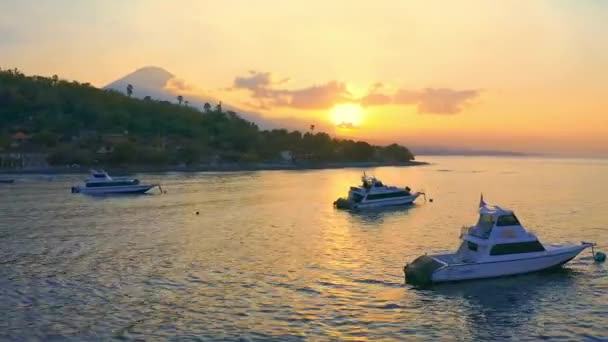 Coucher de soleil à la plage d'Amed, Bali avec des bateaux et des yachts ancrés dans la mer peu profonde et le mont Agung en arrière-plan. BALI, INDONÉSIE. 15 JUILLET 2019 Vue aérienne 4K — Video