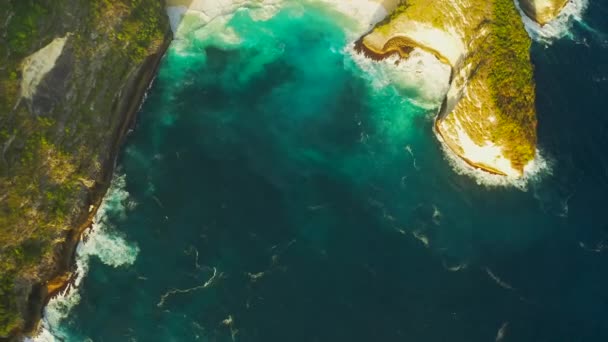 Plaża Kelingking na wyspie Nusa Penida, Bali, Indonezja. Niesamowity widok na dziką przyrodę piaszczystej plaży z gór skalistych i lazurowej laguny z czystej wody Oceanu Indyjskiego o zachodzie słońca. Widok z powietrza 4K — Wideo stockowe