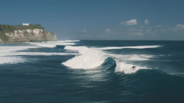 Surfař jezdí na velkých vlnách na Blue Point Beach. Indický oceán v Uluwatu, Bali, Indonésie. Letecký pohled 4K — Stock video