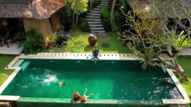Mutlu aile tropik bir cennette lüks bir sonsuzluk havuzunda yüzer ve dinlenir. Anhera Süit Spa, Ubud, Bali, Endonezya - 15 Temmuz 2019.