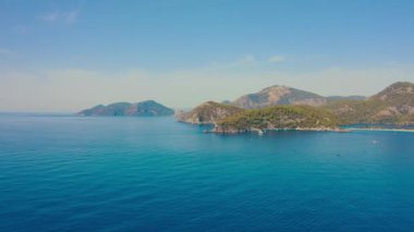 Oludeniz, Türkiye 'deki Blue Lagoon' un inanılmaz hava manzarası. Dağlarla, yeşil ormanlarla, masmavi suyla ve açık güneşli bir günde mavi gökyüzüyle yaz manzarası. Hava görüntüsü 4K.