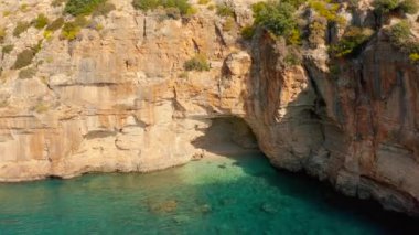 Bir çift gezgin Demre 'den Antalya, Türkiye' ye giden yolda dağda mağarası olan gizli bir koyda yüzüyor. Hava görüntüsü 4K.