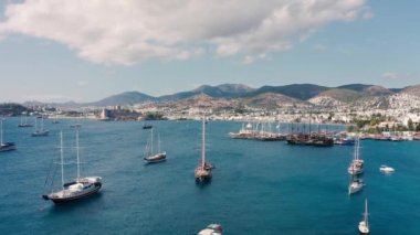 Güneşli yaz gününde Bodrum, Türkiye 'de yelkenli tekneleri ve yatları çeken insansız hava aracı görüntüleri. Havadan görünüm 4K.