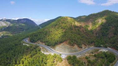 Arabalar dağlık bir bölgede manzaralı bir otoyol boyunca yol alırlar. Hava üst görünümü 4K.