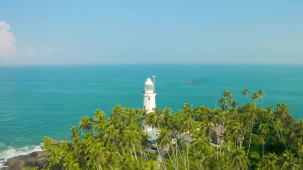 Panoramiczny widok na starą białą latarnię morską stojącą na wybrzeżu tropikalnej wyspy w pobliżu Sri Lanki. Widok z powietrza 4K. — Wideo stockowe