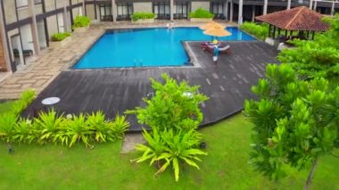 Mutlu aile Sri-Lanka 'da yüzme havuzunda gülümseyip kameraya bakıyor. Ailesiyle yüzme havuzunda güzel küçük bir kız. Hava görüntüsü 4K.