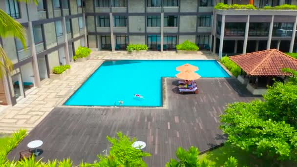 Vista aérea de la familia en la piscina desde arriba, madre feliz y el niño nadan y se divierten en el agua en vacaciones familiares, vacaciones tropicales en el complejo. Vista aérea 4K. — Vídeo de stock