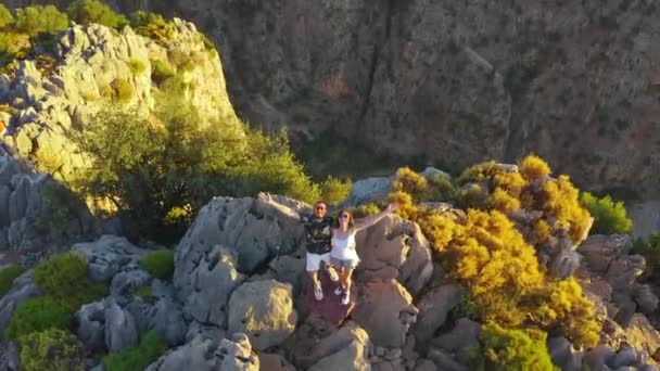 Een verliefd stel staat op de rand van een klif in Butterfly Valley, Oludeniz, Fethiye, Turkije. Reizen, liefde en natuur concept. Luchtfoto 4K. — Stockvideo