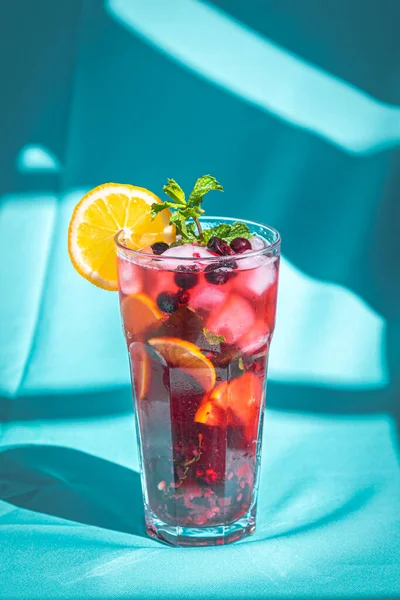 Bevanda estiva rinfrescante con bacca e limone su sfondo blu astratto. — Foto Stock