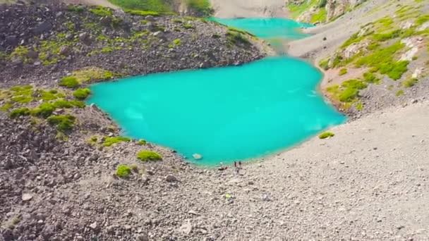 Egy csoport ember egy fenséges türkiz hegyi tó mellett Kanadában. Légi felvétel 4K. — Stock videók