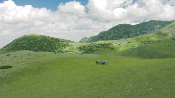 Paisagem campos verdes nas colinas da montanha com grupo de turistas voando em helicóptero. Conceito de estilo de vida turístico. Aerila view 4K. — Vídeo de Stock