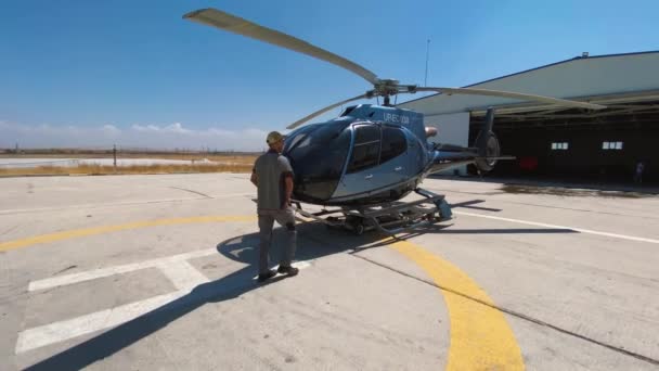 Механик транспортирует вертолет Airbus в ангар самолета. 15 мая 2021 года - Шымкент, Казахстан. — стоковое видео