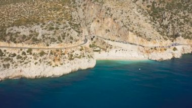 Kas ve Kalkan şehirleri arasında yer alan Türk Akdeniz 'indeki Kaputas plajı. Yol sahil boyunca uzanıyor. Hava görüntüsü 4K.