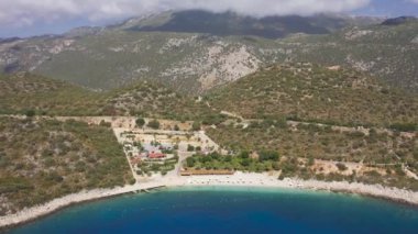 Beyaz kum Belediyesi plajı ve turkuaz deniz bulutlardaki yüksek dağların arka planına karşı, Kas, Türkiye. Hava görüntüsü 4K.