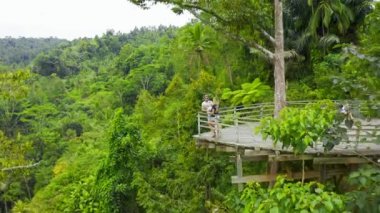 Aerial view young couple on the observation deck in the form of a boat in the jungle in Bali, Indonesia.