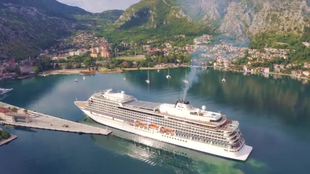 Stort cruiseskip i Kotor havn med fjellbakgrunn, Montenegro. Sett fra luftfartøy 4K – stockvideo