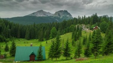 Karadağ 'ın Durmitor milli parkındaki çam ve dağlar arasında geleneksel eve dramatik bir bakış açısı. Zaman Dilimi 4K.