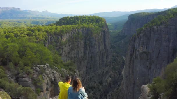 Мужчина и женщина сидят на краю каньона Тазы в Национальном парке на Манавгате, Анталья, Турция. Вид с воздуха 4K. — стоковое видео