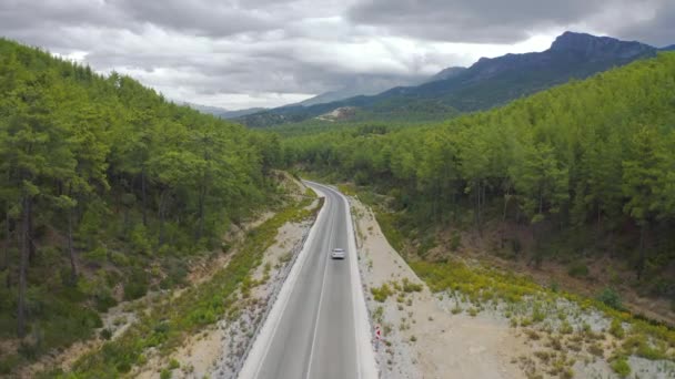 이 자동차는 터키 안탈리아의 마나 브 갓에 있는 녹색 숲 과 함께 산길을 따라 달리고 있다. 공중에서 본 4K. — 비디오