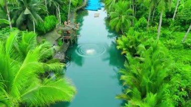 Yüzen genç erkek ve kadınların havası, açık mavi Maasin Nehri 'nde tropik palmiye ağaçları, Maasin, Güney Leyte, Filipinler.
