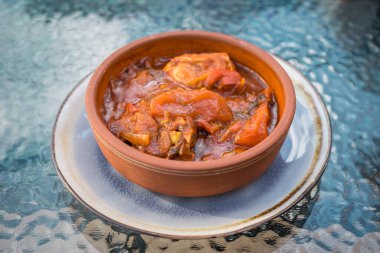 Sebzeli ve baharatlı Gürcü tavuk tabağı cam bir masanın üzerinde.