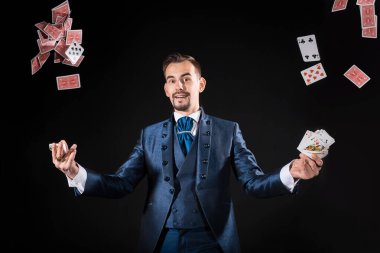 Siyah arka plan ve uçuş kartlarında mavi ceketli bir sihirbaz.