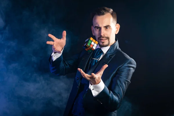 Mavi kuyruklu bir sihirbaz bir rubik küple havalanır.
